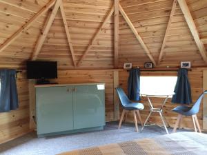 a room with a bed and two chairs and a television at La cabane de l'Atelier in Bomal