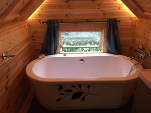 bañera en una habitación con ventana en La cabane de l'Atelier, en Bomal