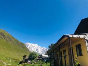 una casa in un villaggio con montagne sullo sfondo di Guesthouse Ivas a Ushguli