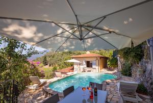 a pool with a table and chairs and an umbrella at Villa Romantica Sea View in Camaiore
