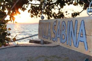 a sign on the beach with the ocean in the background at Villa Sabina - Apartments Kroatien in Ražanac