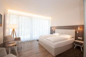Un dormitorio con una gran cama blanca y una mesa en Hotel Jasmin, en Merano