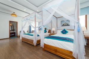 a bedroom with two beds and a canopy bed at Hoi An Sea Village Homestay in Hoi An