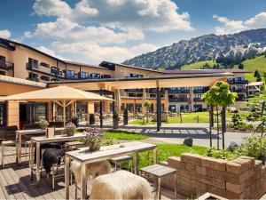 un patio avec des tables et des parasols en face d'un bâtiment dans l'établissement Panoramahotel Oberjoch, à Bad Hindelang