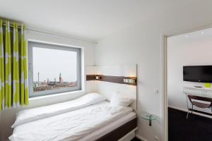 Schlafzimmer mit einem Bett mit einem Fenster und einem TV in der Unterkunft Wakeup Copenhagen - Carsten Niebuhrs Gade in Kopenhagen