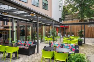 un patio con sillas y mesas verdes y un edificio en Thon Hotel Maritim, en Stavanger