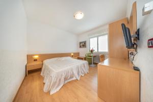 ein Schlafzimmer mit einem Bett und einem TV in einem Zimmer in der Unterkunft Hotel Karinhall in Trient