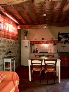 eine Küche mit einem Tisch, 2 Stühlen und einem Kühlschrank in der Unterkunft Podere La Fausta in Serravalle Pistoiese