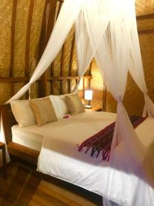 um quarto com uma cama com cortinas brancas em Uluwatu Sunrise em Ungasan