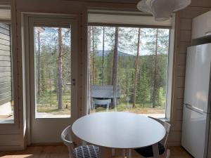una cocina con una mesa blanca frente a una ventana en Villa LumiHelmi A & B en Äkäslompolo
