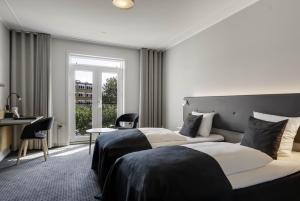 una camera da letto con due letti, una scrivania e una finestra di Hotel Svendborg a Svendborg