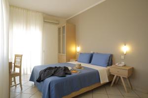 - une chambre avec un lit bleu, une table et une chaise dans l'établissement Stratos Hotel, à Afytos
