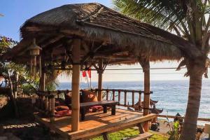 a wooden deck with a hut on the beach at Eka Purnama Cottages in Amed