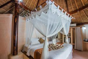 a bedroom with a canopy bed with white curtains at Sanghyang Bay Villas in Nusa Lembongan