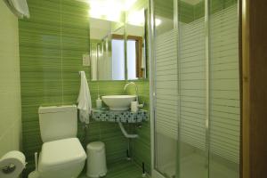 a green bathroom with a toilet and a sink at Stratos Hotel in Afitos