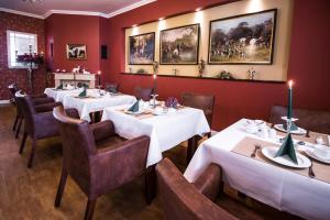 a restaurant with tables and chairs and paintings on the wall at Pension und Restaurant Gutshaus Kaltenhof in Kaltenhof