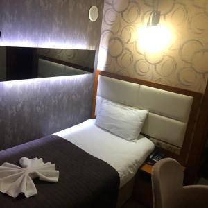 una habitación de hotel con una cama con una flor blanca. en Izmıt Saray Hotel en Kocaeli
