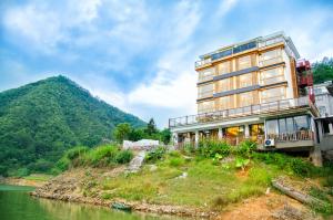 a building on a hill next to a river at The Lake View Deyishe Resort in Thousand Island Lake in Thousand Island Lake