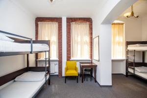 a dorm room with bunk beds and a yellow chair at Hostel Wratislavia in Wrocław