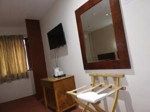 Habitación con espejo, silla y TV. en Floral Hotel en Pasir Gudang