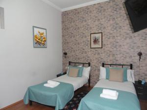 two beds in a room with a brick wall at Apartment Fine Home in Tbilisi City