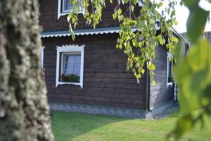Merkiokrantas Pirkia kaime في Puvočiai: منزل به نافذة عليها علبة ورد