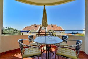 a table and chairs on a balcony with a view of the ocean at Lux Apartman Sofia in Sveti Stefan