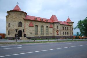 a large brick building with a red roof on a street at Готельно-ресторанний комплекс «Галицький замок» in Ternopil