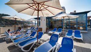 a row of lounge chairs and umbrellas on a beach at Hotel MS Maestranza Málaga in Málaga