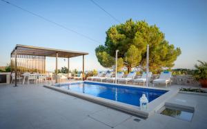a swimming pool with chairs and a gazebo at Villa Moderna Family Friendly in Hvar