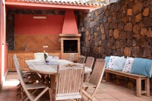a table and chairs on a patio with a stone wall at Villa Santa Rosa Tenerife in Tacoronte