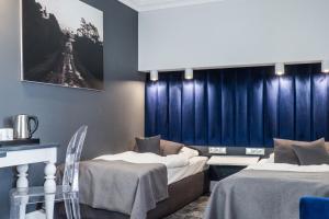 two beds in a room with blue curtains at City Boutique Hotel in Zielona Góra