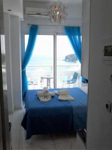 sypialnia z niebieskim łóżkiem i widokiem na ocean w obiekcie Andreas Kanali w mieście Parga