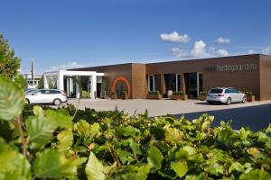 un bâtiment avec deux voitures garées dans un parking dans l'établissement Hotel Hedegaarden, à Vejle