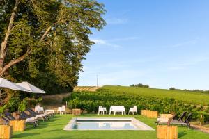 une piscine au milieu d'une pelouse avec des chaises et des tables dans l'établissement Château de Tauzies, The Originals Relais, à Gaillac