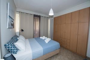 um quarto com uma cama azul e branca e armários de madeira em A beautifull 2nd floor apartment close to the Port em Kalamata