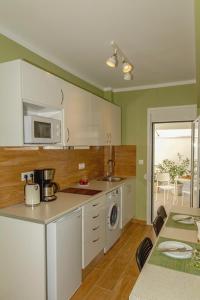 een keuken met groene muren, witte kasten en een tafel bij YOUR ATTIKI HOME vipgreece in Athene