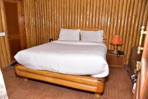 Cama en habitación con pared de madera en Snow King Retreat- Himalayan view , Revolving Restaurant , Pinewood Cottages , Huts , Villas , Rooms , Hydro Pool , Karaoke Music , DJ Night, en Kūfrī