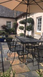 - une table et des chaises avec un parasol sur la terrasse dans l'établissement Aaron Glen Guest House, à Loanhead