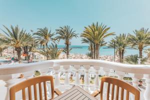 a balcony with a view of the beach and palm trees at Hotel Cleopatra Palace in Playa de las Americas