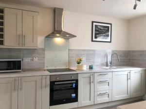 uma cozinha com armários brancos e um forno com placa de fogão em Lloydia em Porthmadog