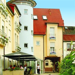 eine Gruppe von Personen, die unter einem Schirm vor einem Gebäude sitzen in der Unterkunft Querfurter Hof in Querfurt