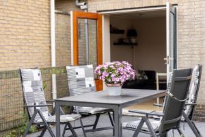 a table and chairs with a vase of flowers on it at T Fiskersplak in Hollum