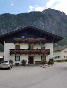 a building with flowers on it with a mountain in the background at Privatzimmer Bundschuh in Amlach