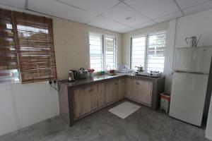 a kitchen with a white refrigerator and wooden cabinets at Tung's Factoria Cameron Highland in Cameron Highlands
