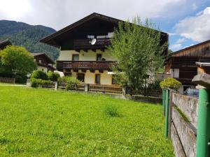 a house with a fence and a green field at Privatzimmer Bundschuh in Amlach