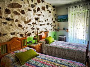 1 dormitorio con 2 camas y pared de piedra en El Triskel de Chumbea, alojamiento excepcional con maravillosas vistas a 5km de Béjar, en Navalmoral de Béjar