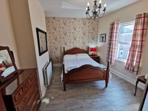a bedroom with a bed and a dresser and a window at The Garden in Barrow in Furness
