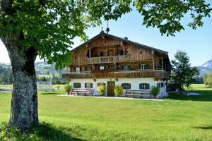 ein großes Holzgebäude auf einem Feld mit einem Baum in der Unterkunft Ferienhaus Hinterebenhub in Hopfgarten im Brixental