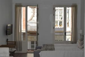 a bedroom with a white bed and a balcony at Modern studio flat close to Plaza Merced in Málaga
